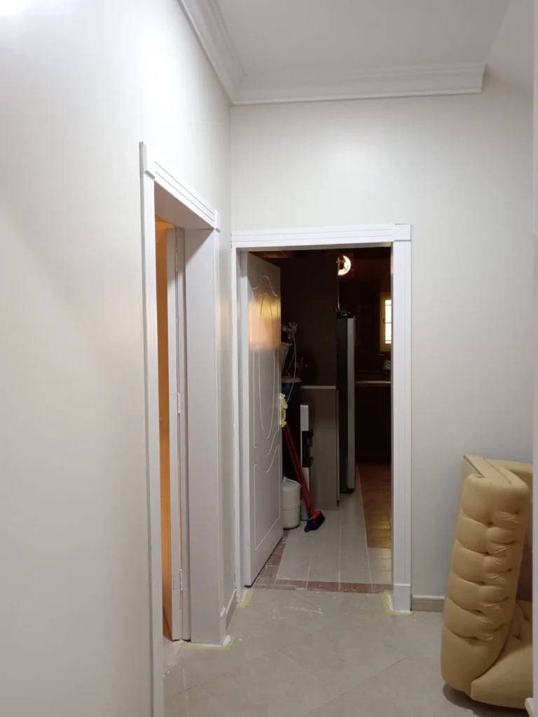 ممر داخلي بدهانات بيضاء وإطارات أبواب خشبية للمطبخ، عمل معلم دهانات بالرياض