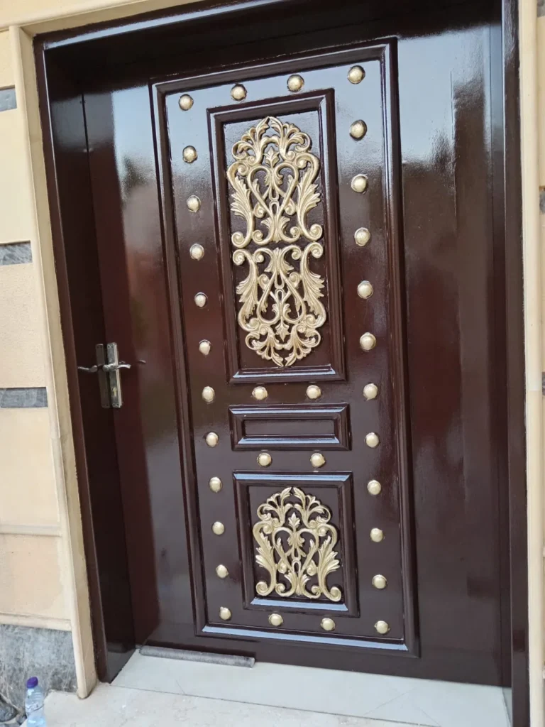 باب مرصع بزخارف ذهبية باشكال هندسية تم دهنه بدهانات بنية من قبل معلم دهانات الرياض