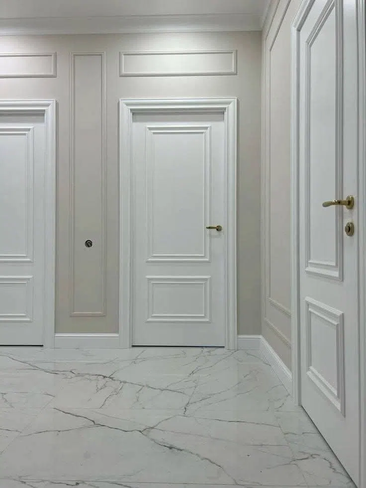 تشطيب دهانات يبرز تناسق اللون الرمادي مع الأبواب البيضاء المطلية بطبقات متقنة، وإطارات حائط