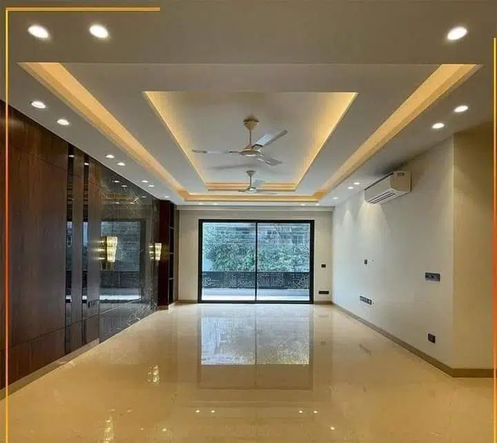 صالة داخلية حديثة بدهانات فاتحة، سقف جبس مع إضاءة مخفية، أرضية لامعة ونوافذ زجاجية واسعة